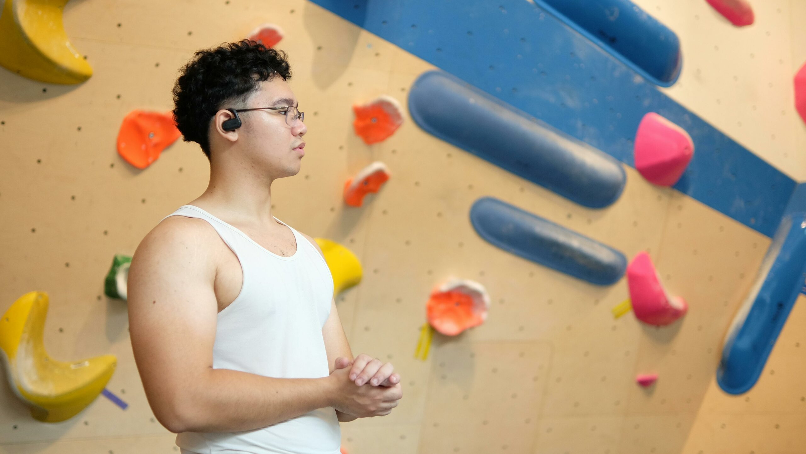 Junger Mann bereitet sich im Fitnessstudio aufs Bouldern vor. Klettergriffe im Hintergrund.