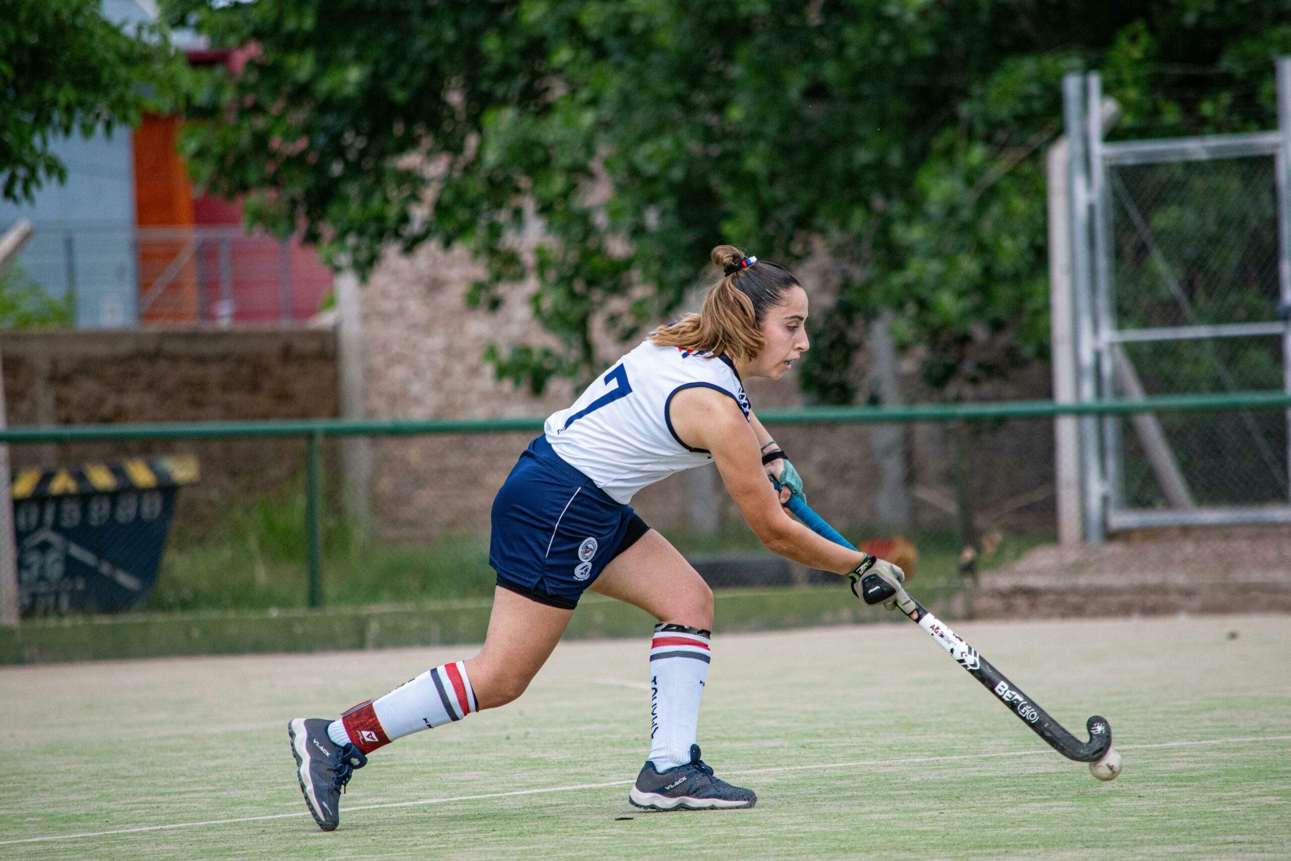 Feldhockeyspielerin schlägt den Ball während eines Spiels im Freien.