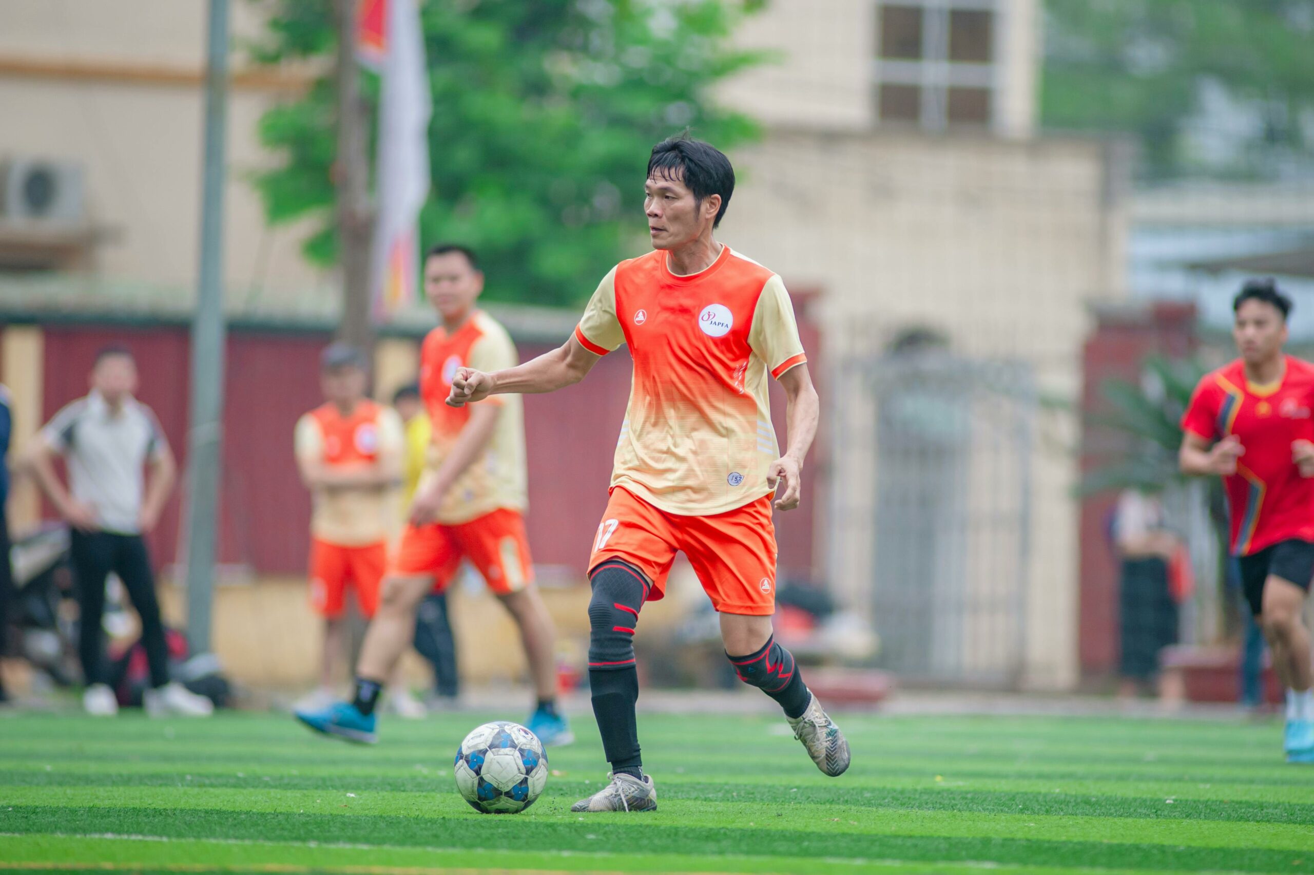 Dynamisches Fußballspiel auf einem Feld in Hanoi, bei dem die Spieler in Aktion zu sehen sind.
